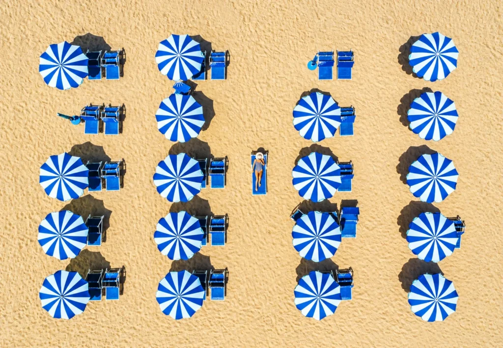Ombrelloni blu e bianchi sulla spiaggia, vista dall’alto