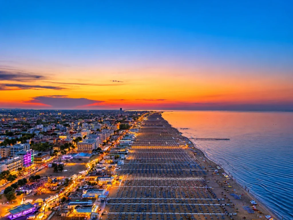 Panorama del lungomare riminese al tramonto con luci e spiaggia